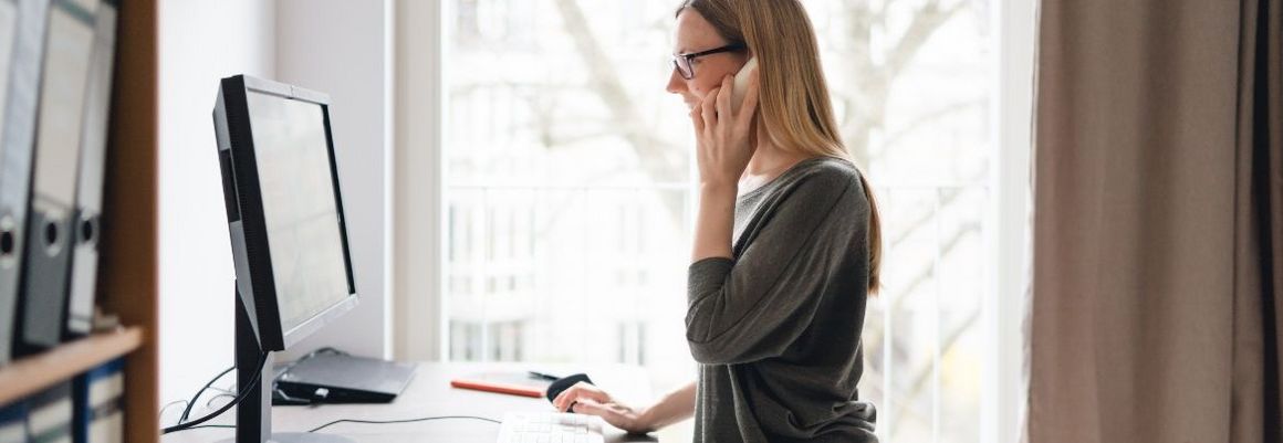 Person telefoniert am Computer.
